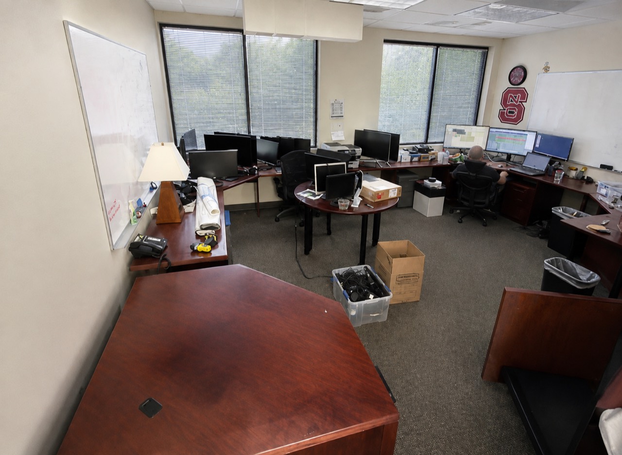 Office room with desks, monitors, and boxes before a commercial cleanout