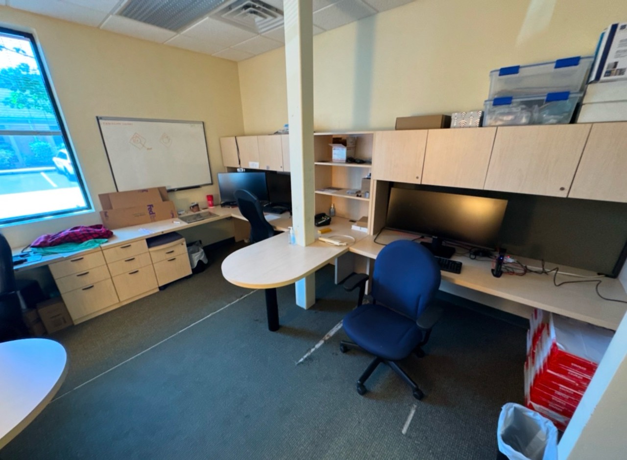 Office room with desks, monitors, and boxes before a commercial cleanout